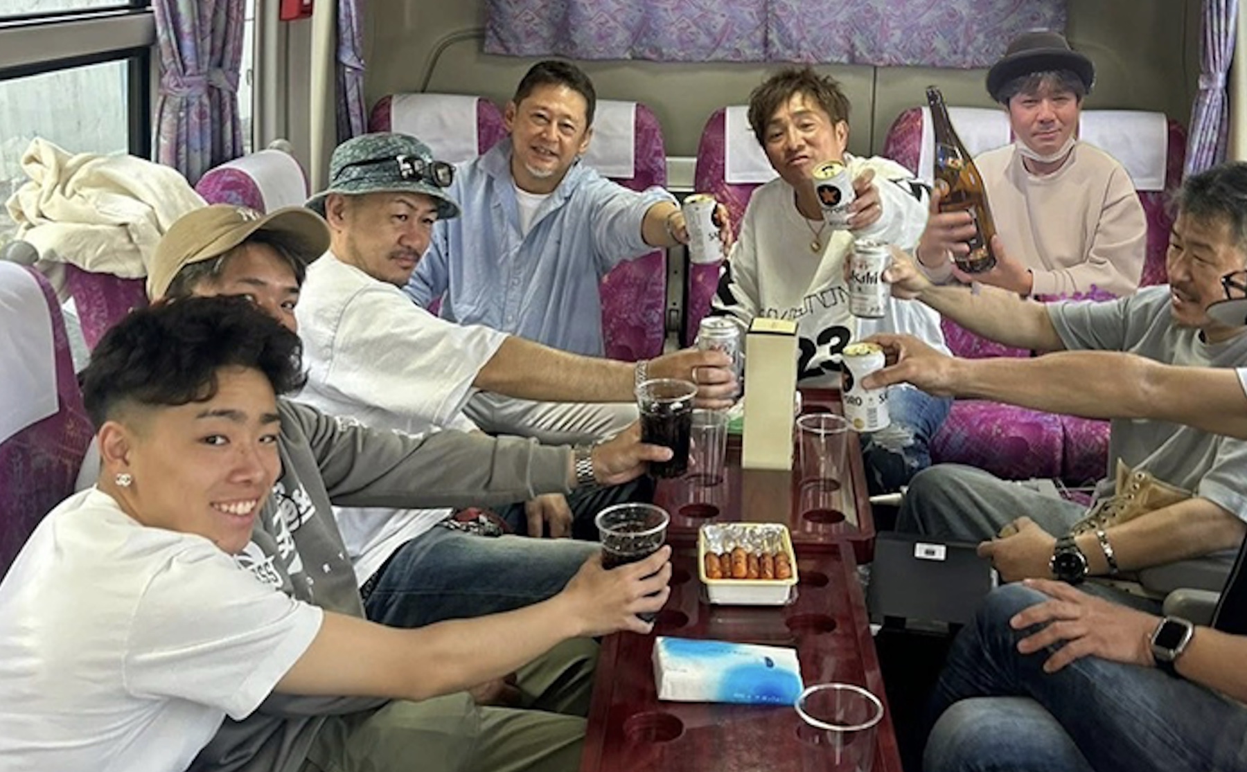 社員旅行のバス車内で乾杯する社員